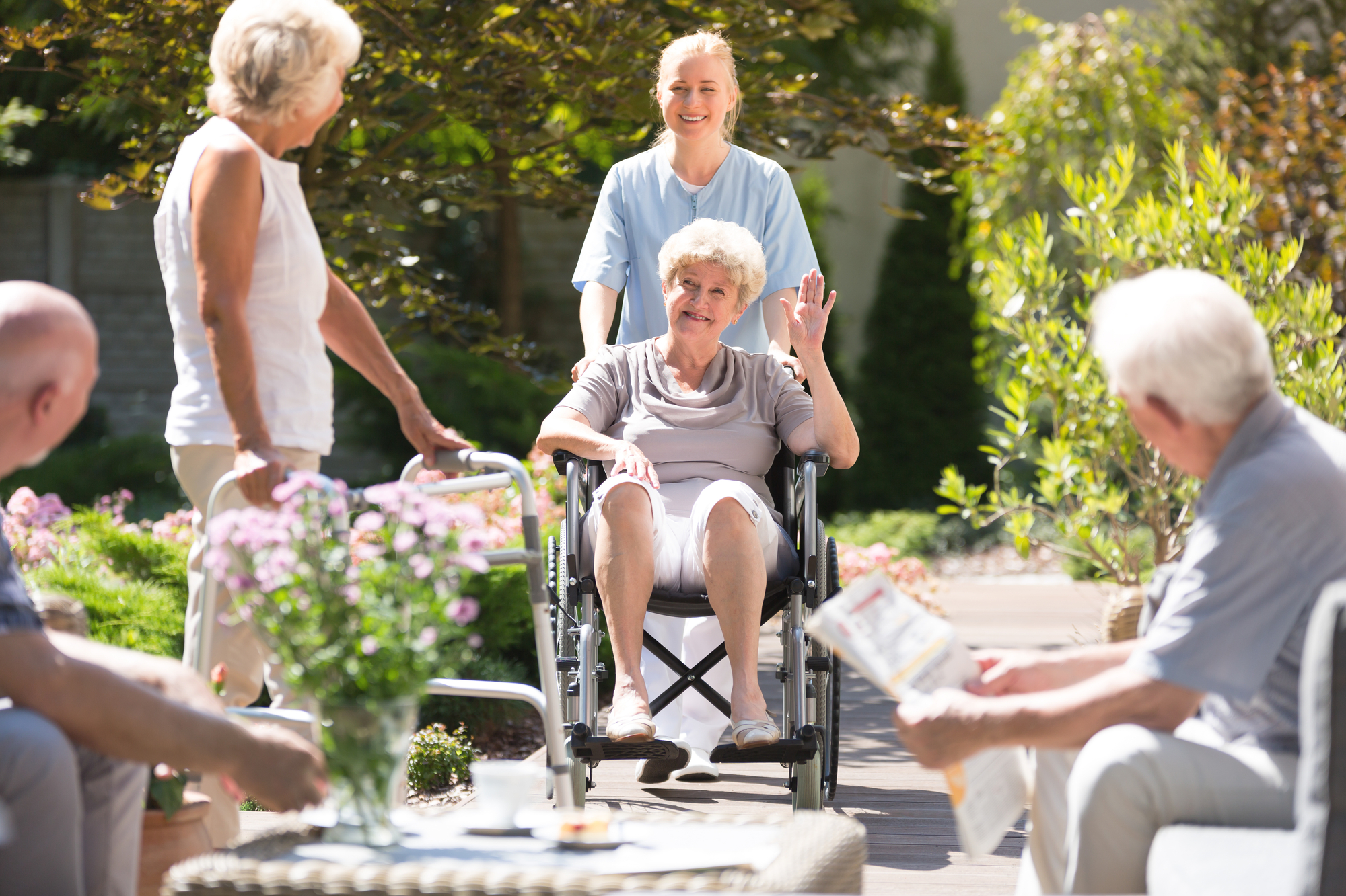 Happy Grandma In Wheelchair Waving To Her Friend